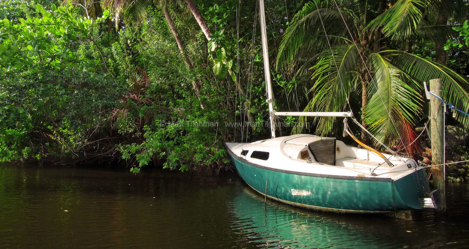 Fine art stock photograph of old derelict sailboat in Florida jungle. A once-loved sailboat sits idly decaying in the forests along Fort Lauderdale's New River.