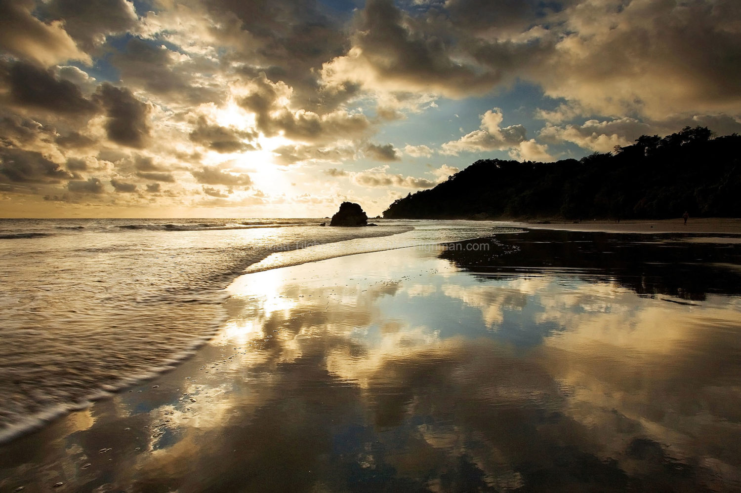 Fine art stock photograph from Manuel Antonio Park, Costa Rica. The sunset becomes reflected perfectly by the thin film of water left on the sand as the waves retreat.